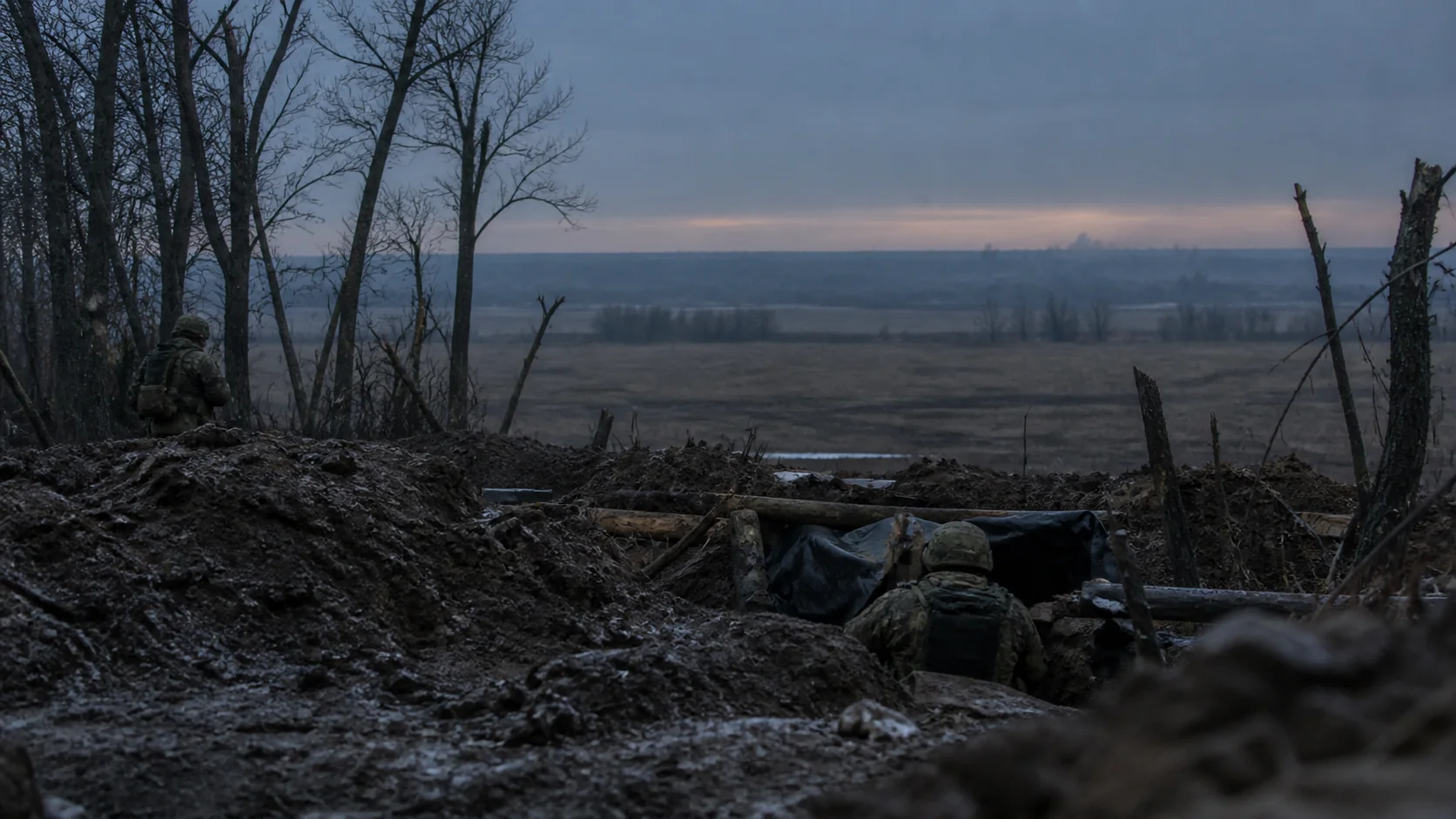 Українські військові в оборонній позиції біля лісосмуги у сутінках